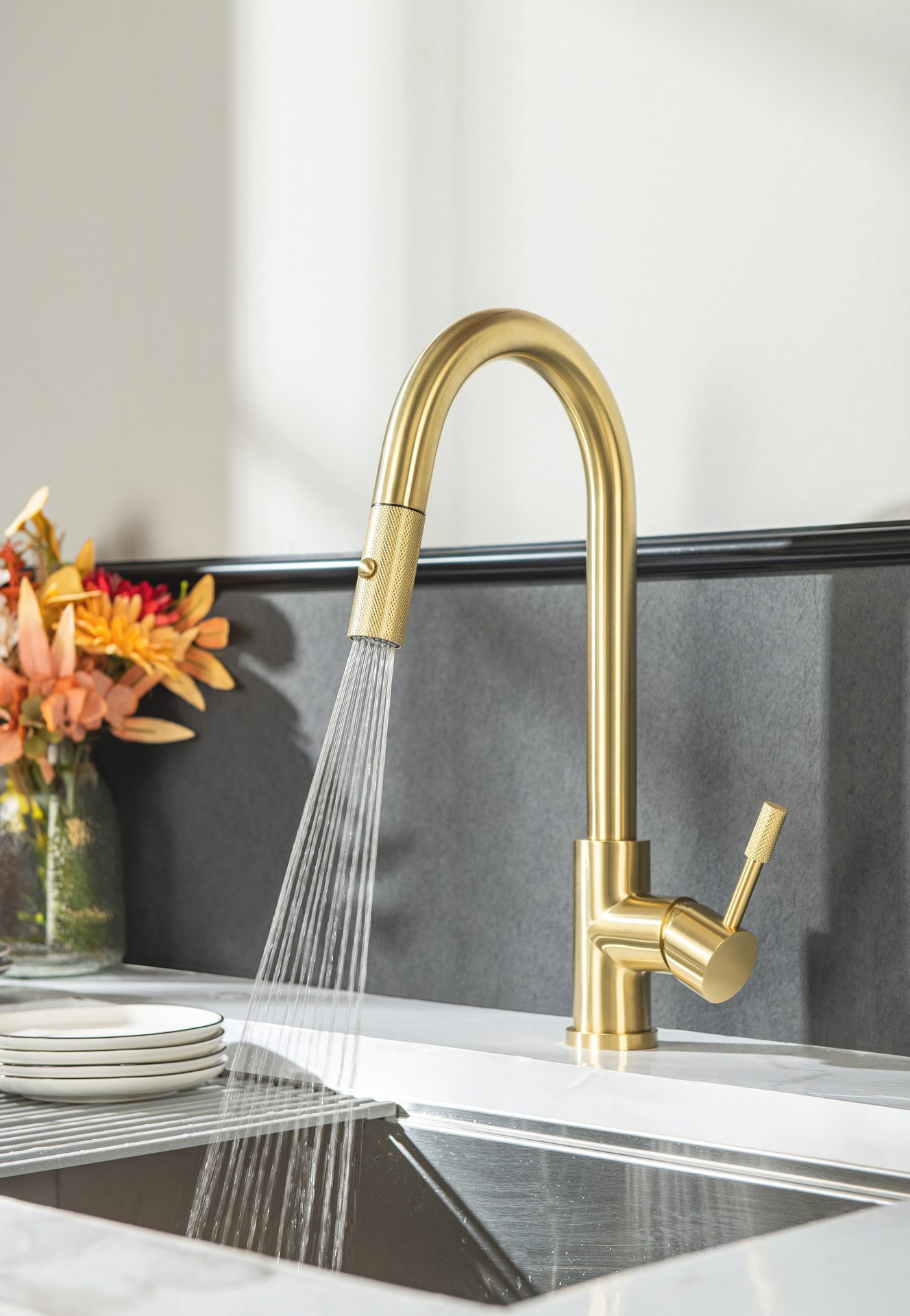 Golden kitchen faucet spraying water into a sink.
