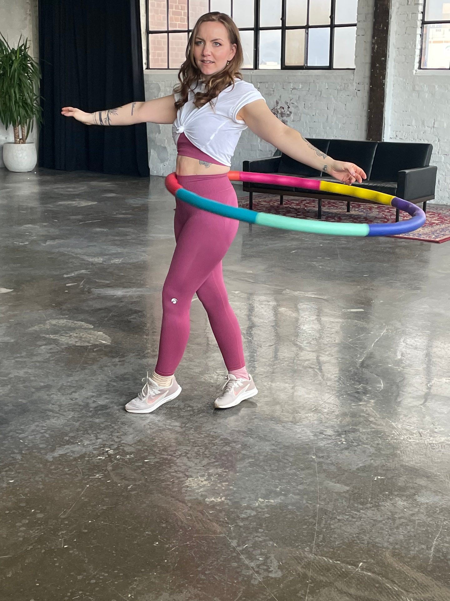 Woman in activewear hula hooping with a colorful hoop.