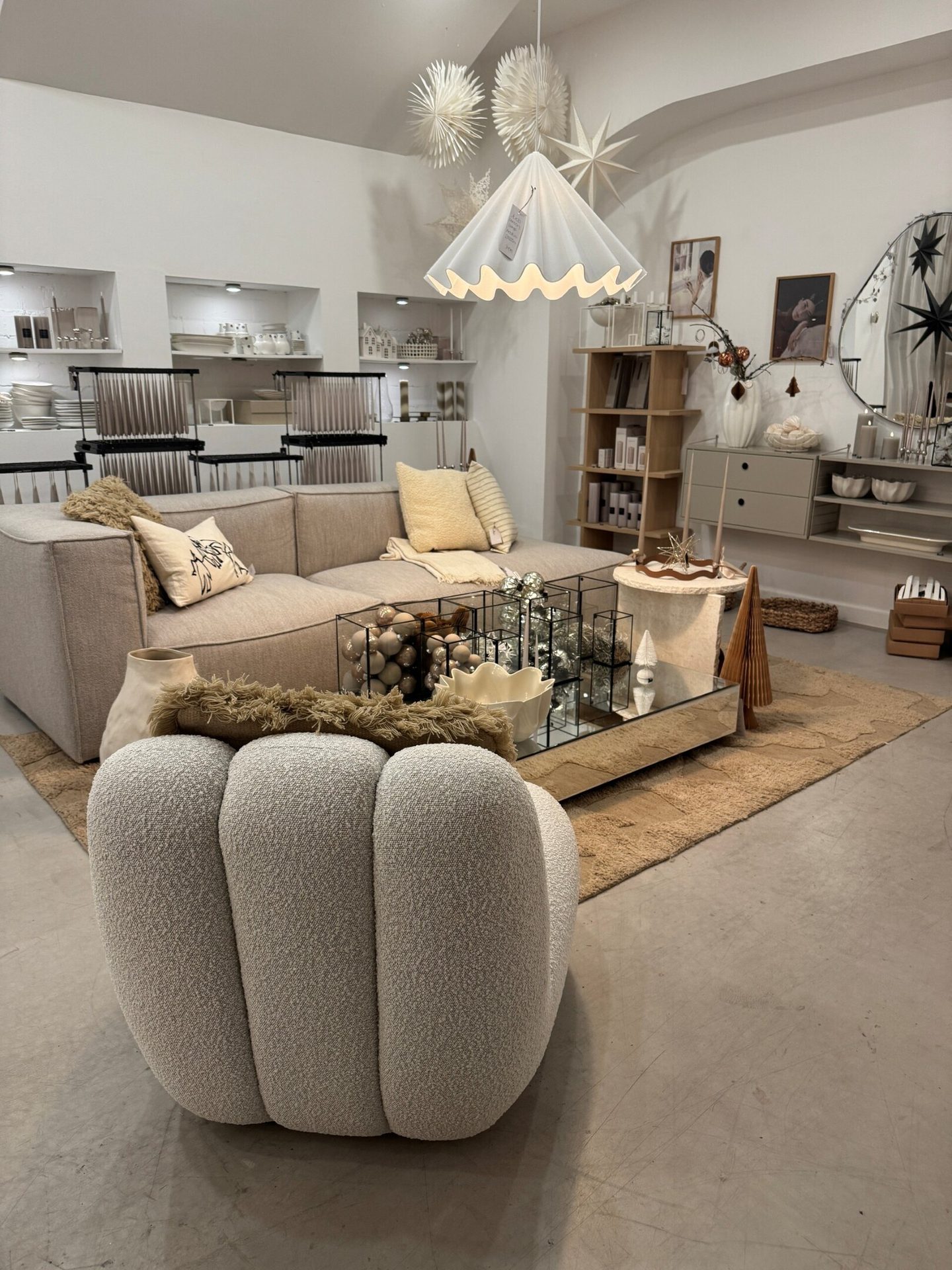 A modern, neutral-toned living room scene with a sofa, armchair, coffee table, and festive decor.