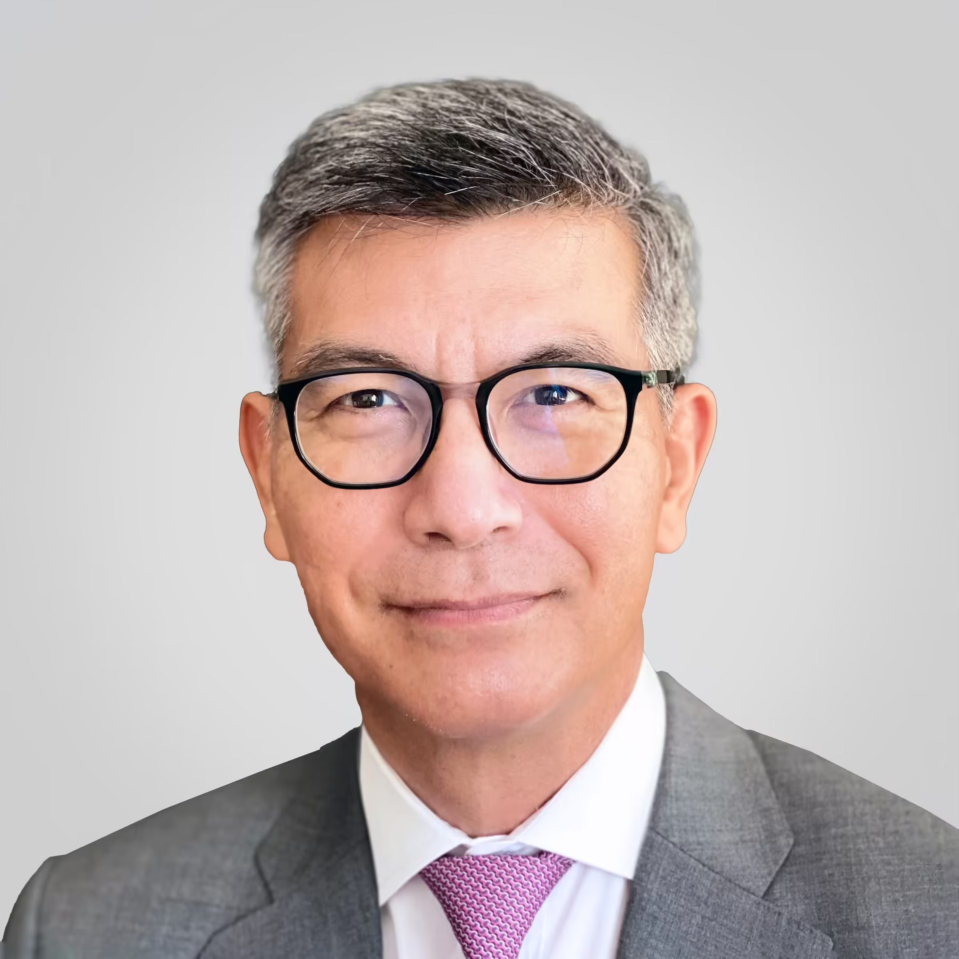 Smiling Asian man with gray hair, glasses, suit & tie.