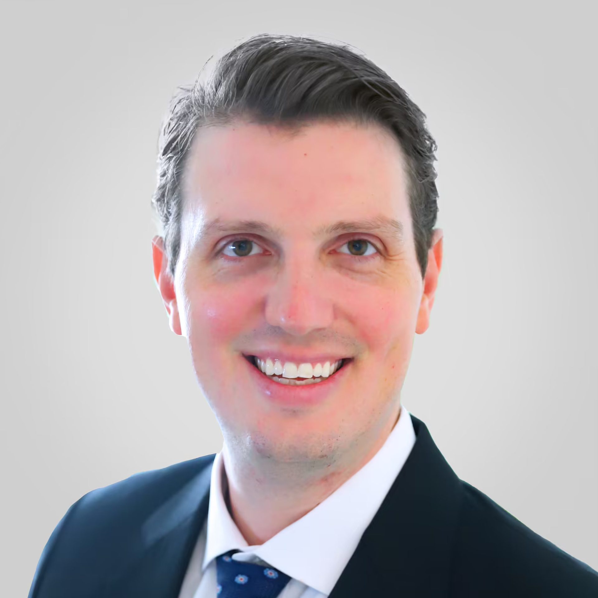 Headshot of a smiling man in a suit and tie.