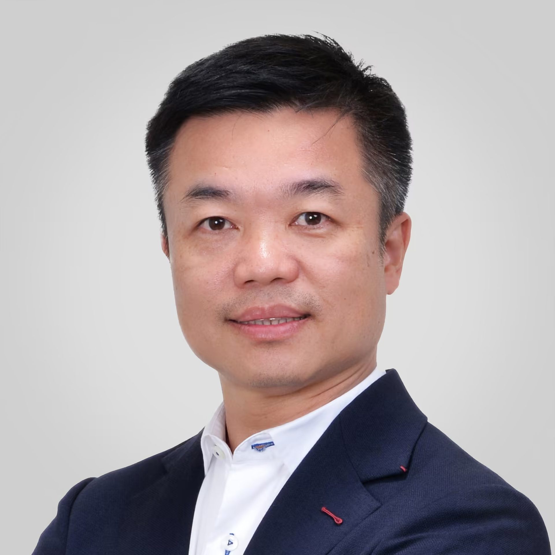 Smiling Asian man in a dark suit, headshot.