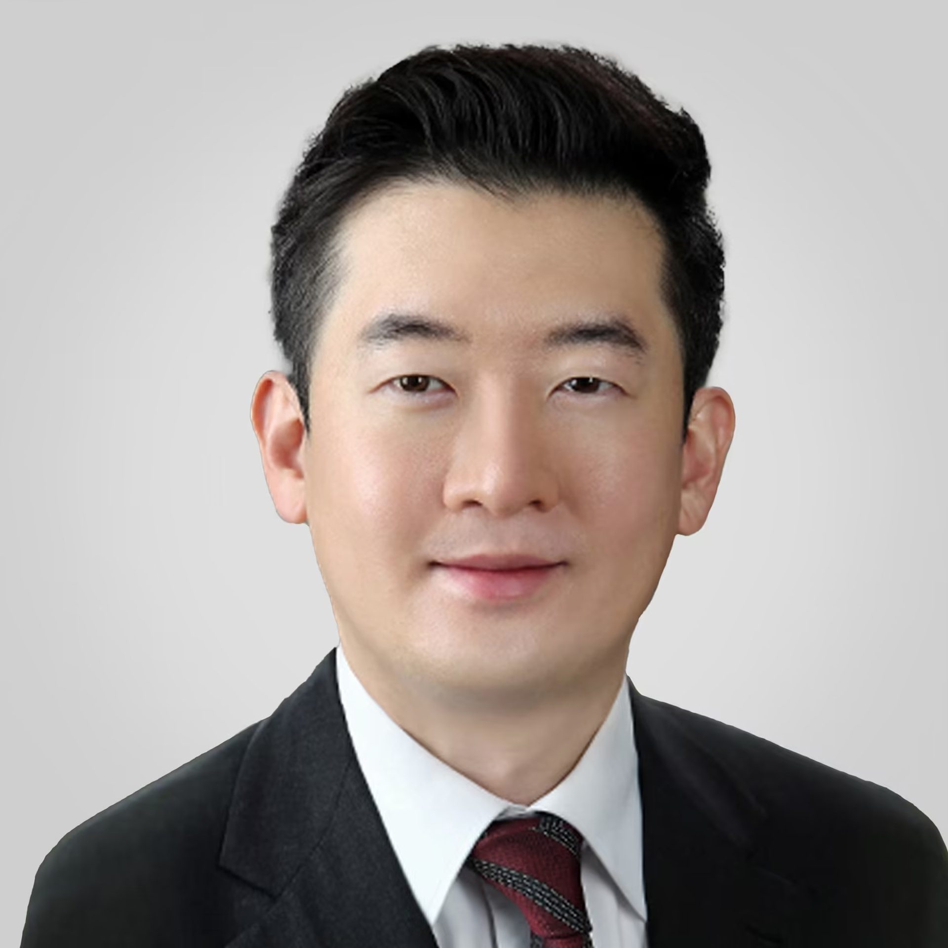 Headshot of an East Asian man in a suit and tie, smiling.