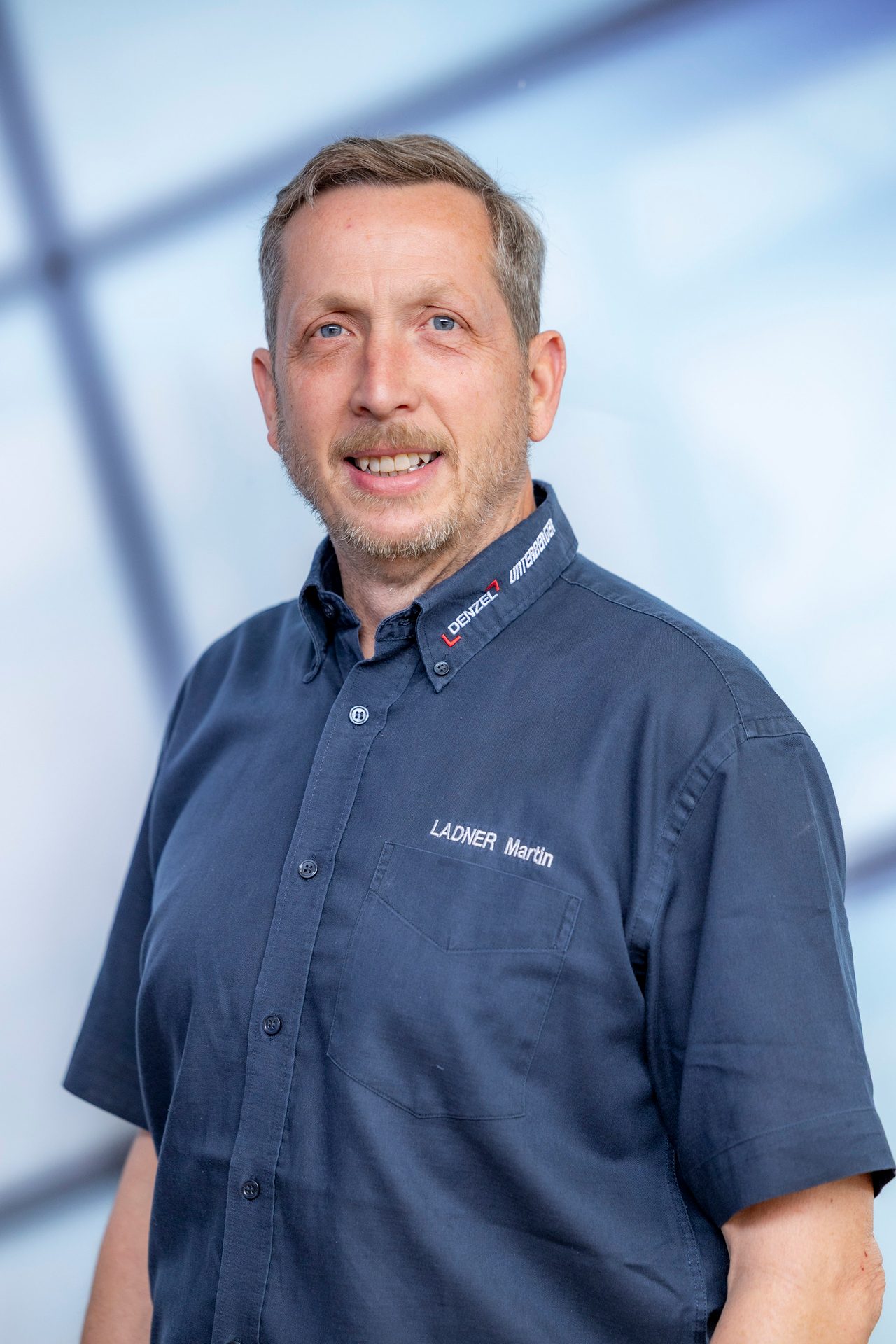 Smiling man in a blue shirt with "LADNER Martin" and company logos.