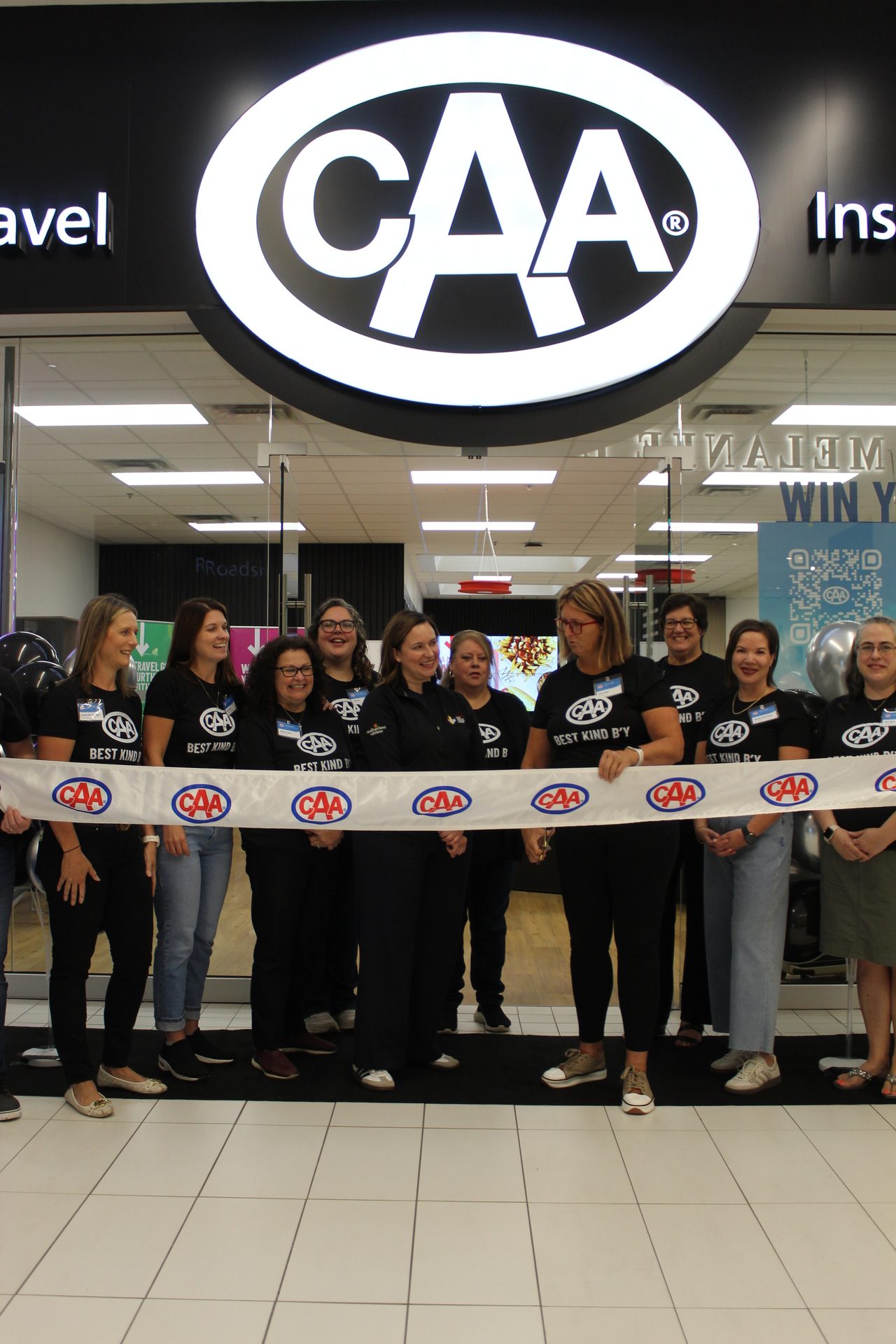 Women in CAA shirts celebrate a grand opening with a ribbon cutting.