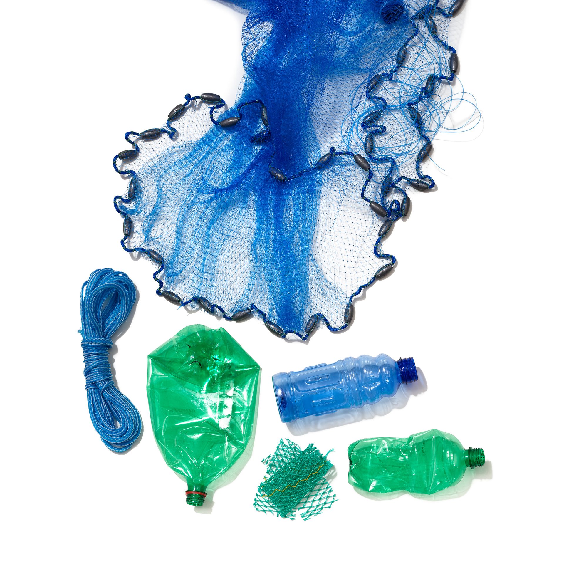 A blue fishing net, coiled rope, and crushed green and blue plastic bottles on a white background.
