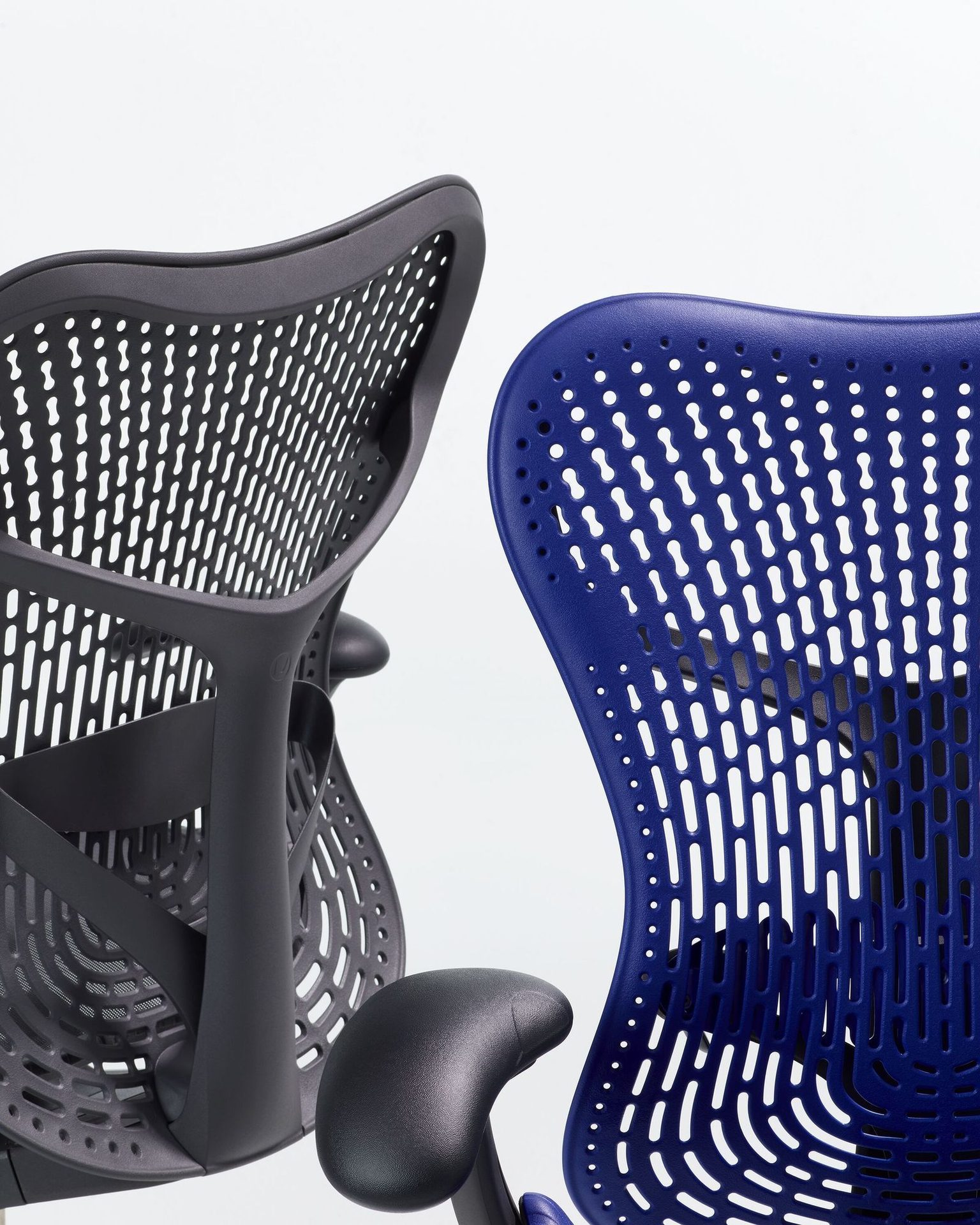 Two office chairs with perforated backs, one black and one blue, against a white background.