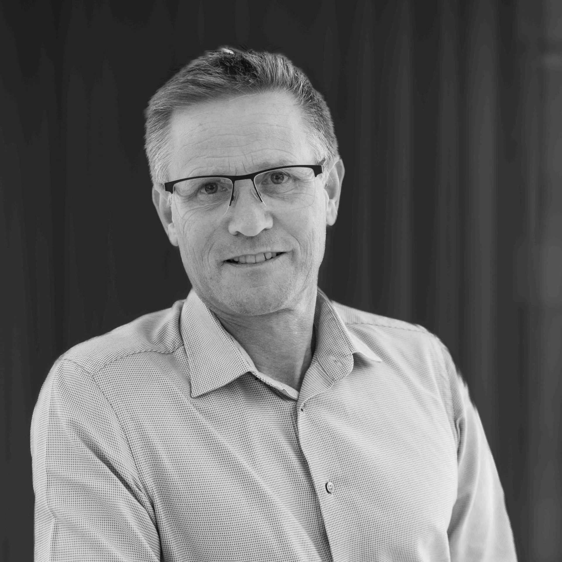 Smiling man in glasses, black and white portrait.