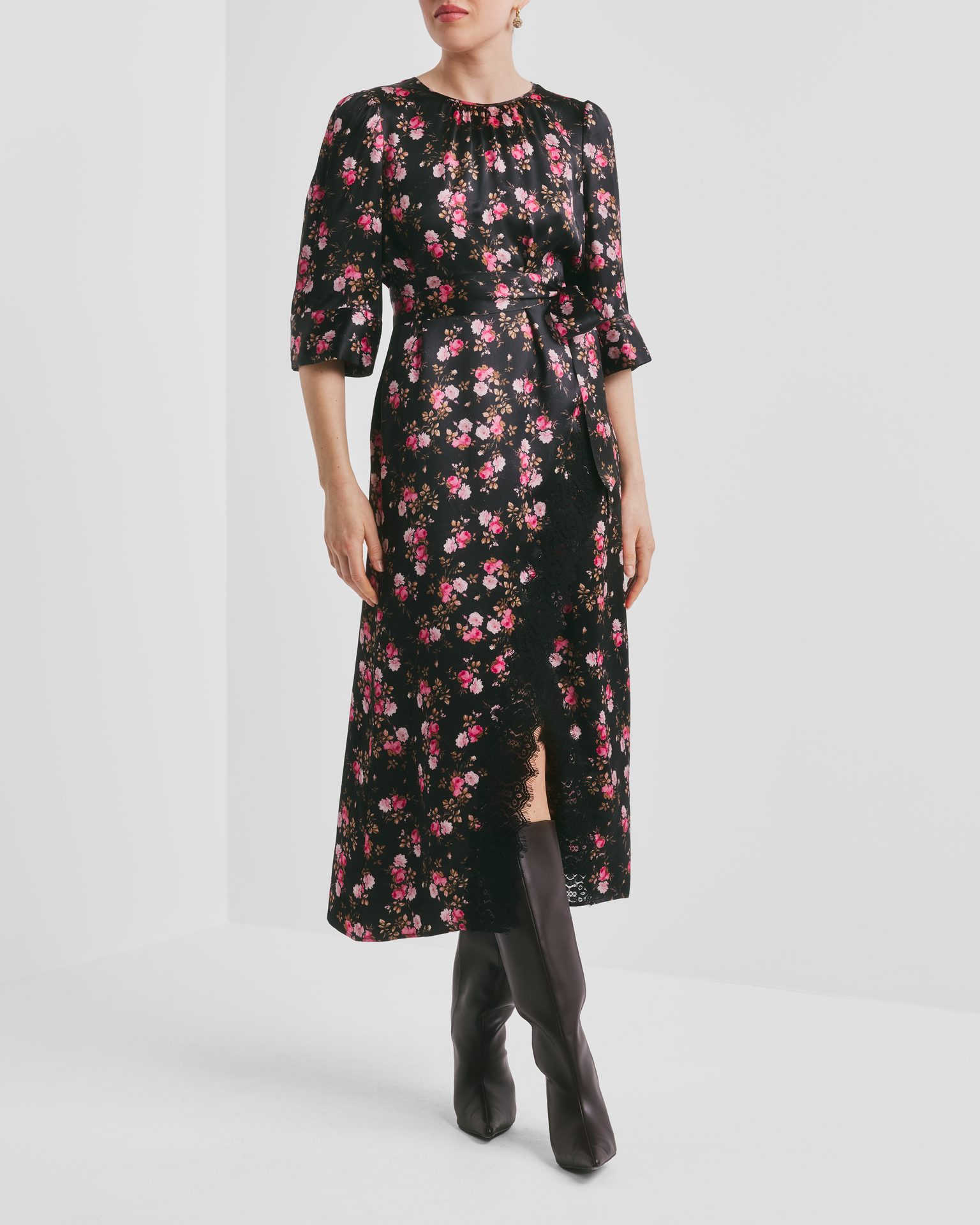 Woman in black floral dress with pink roses, lace detail, and dark boots.