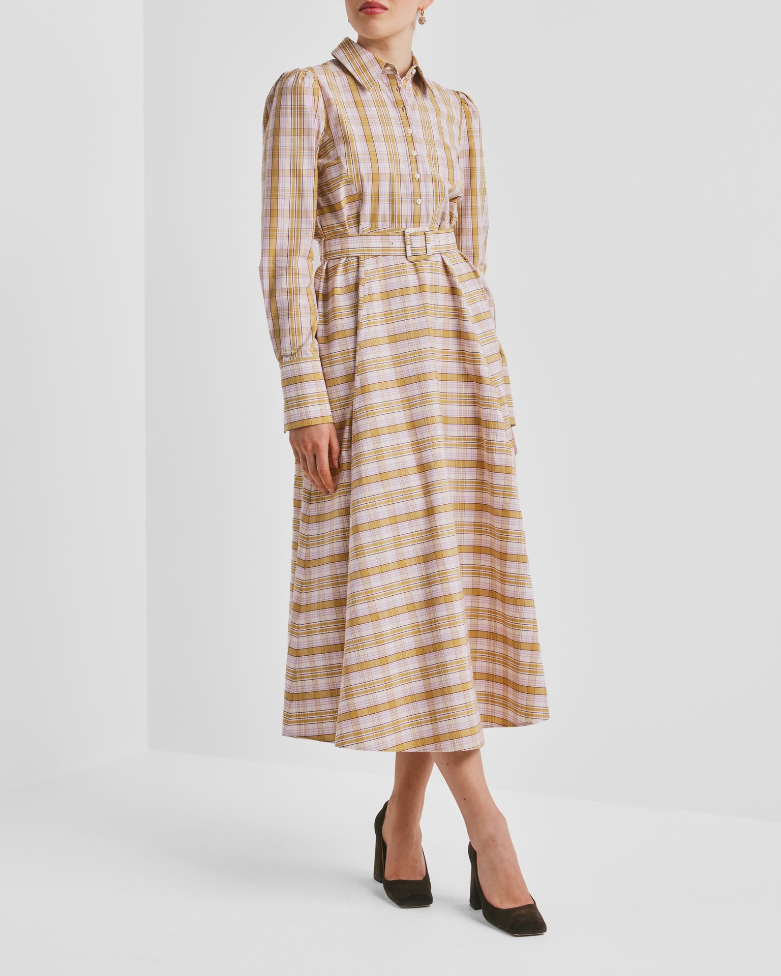 Person wears yellow and pink plaid belted midi shirt dress and dark pumps.