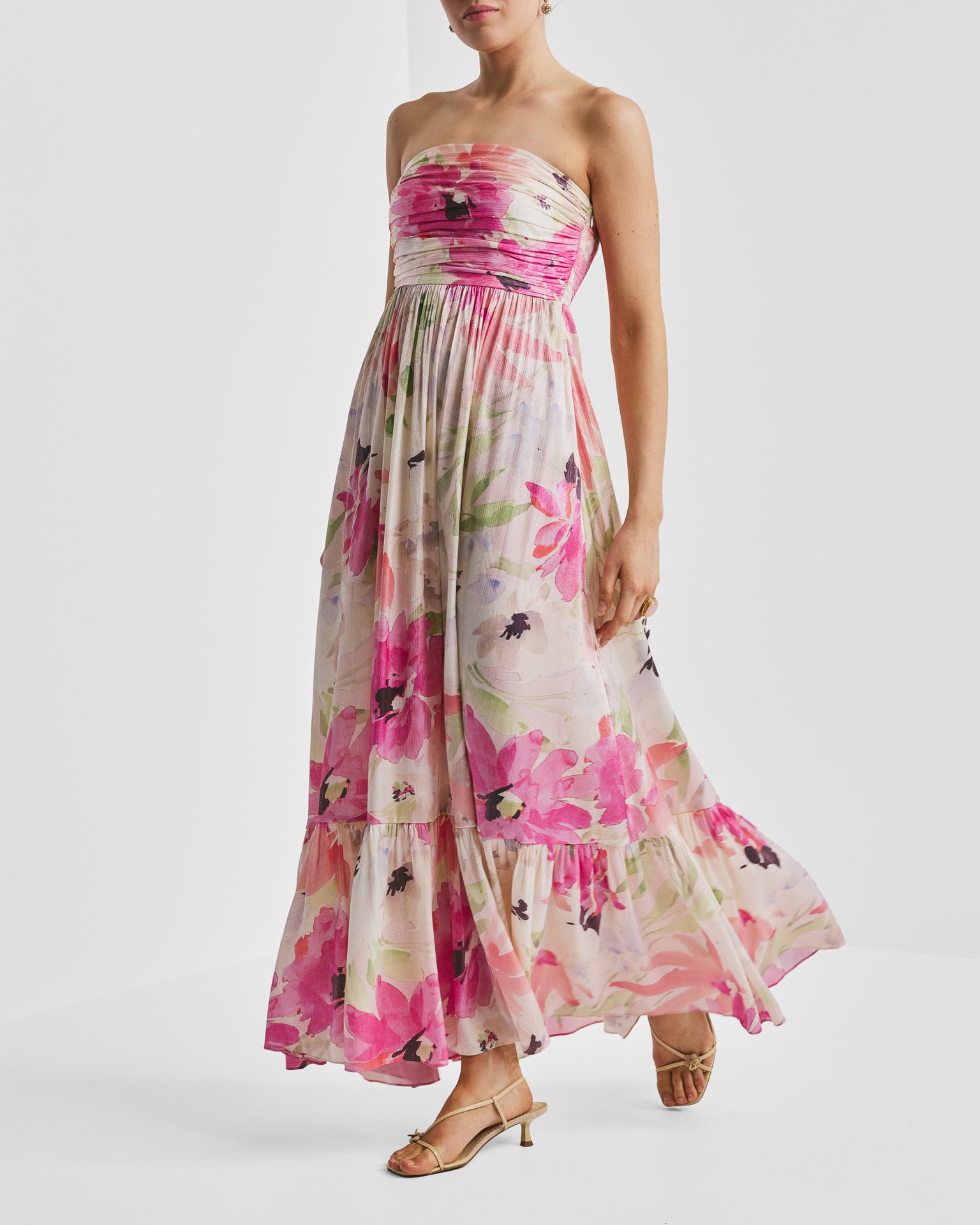 Woman in a vibrant pink floral strapless maxi dress with light sandals.