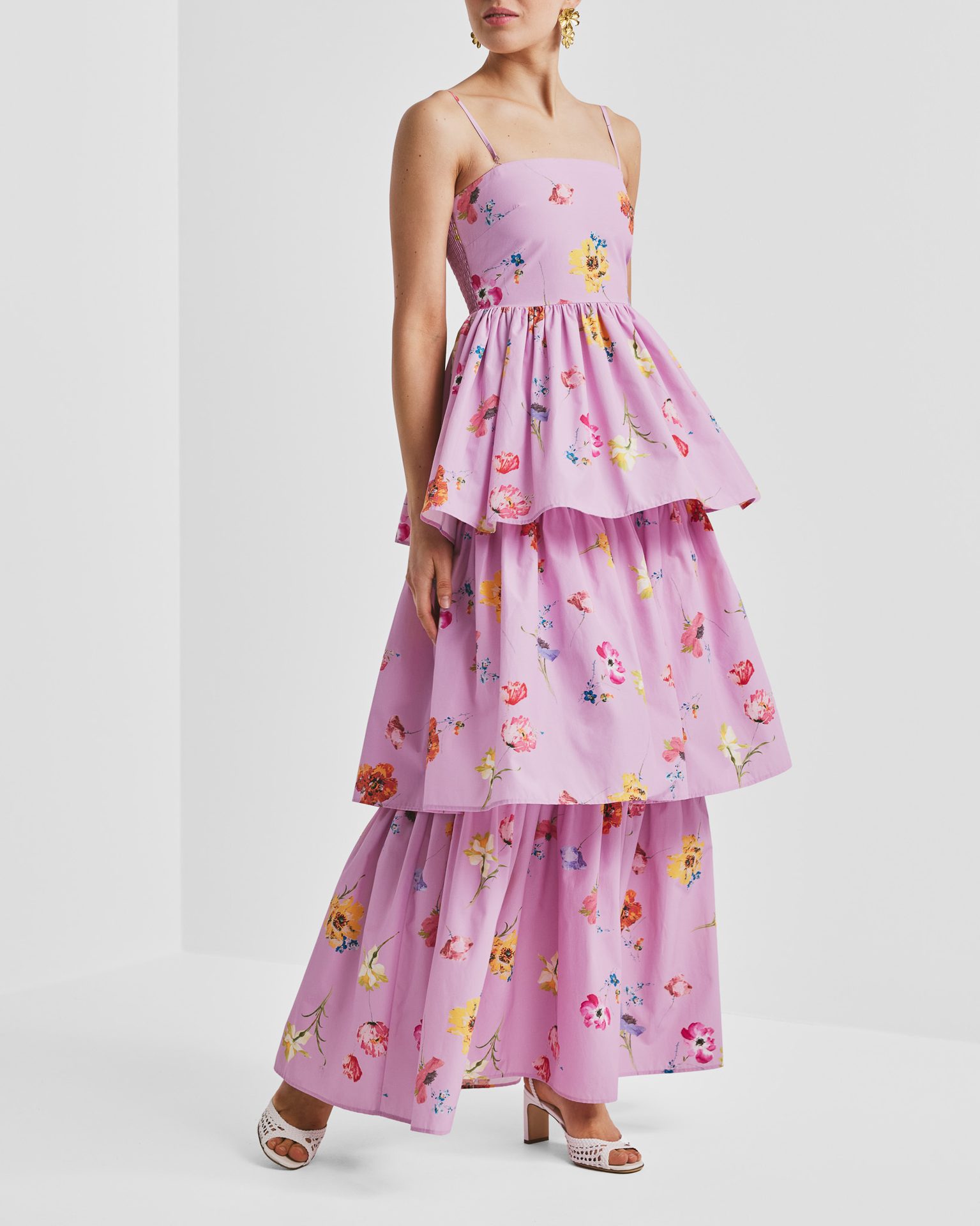 Lavender tiered floral maxi dress with gold earrings and white heels.