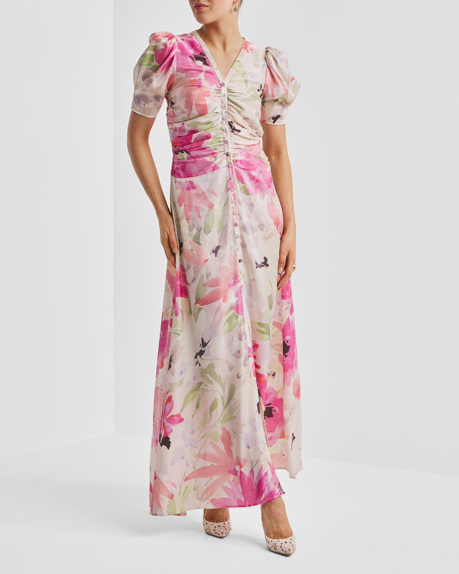 Woman in a V-neck pink floral maxi dress with puff sleeves and ruched front.