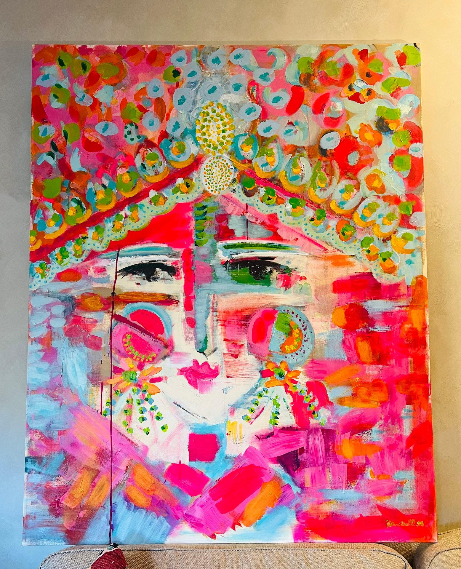 A vibrant, abstract painting of a face in bright pink, orange, blue, and green hues.