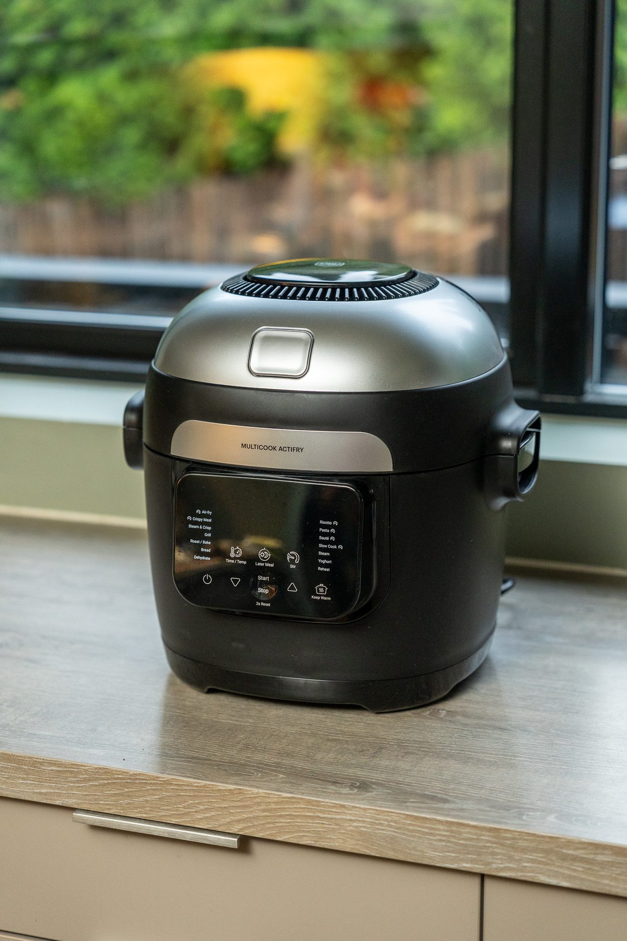 A black and silver Multicook Actifry appliance on a kitchen counter, with its control panel visible.