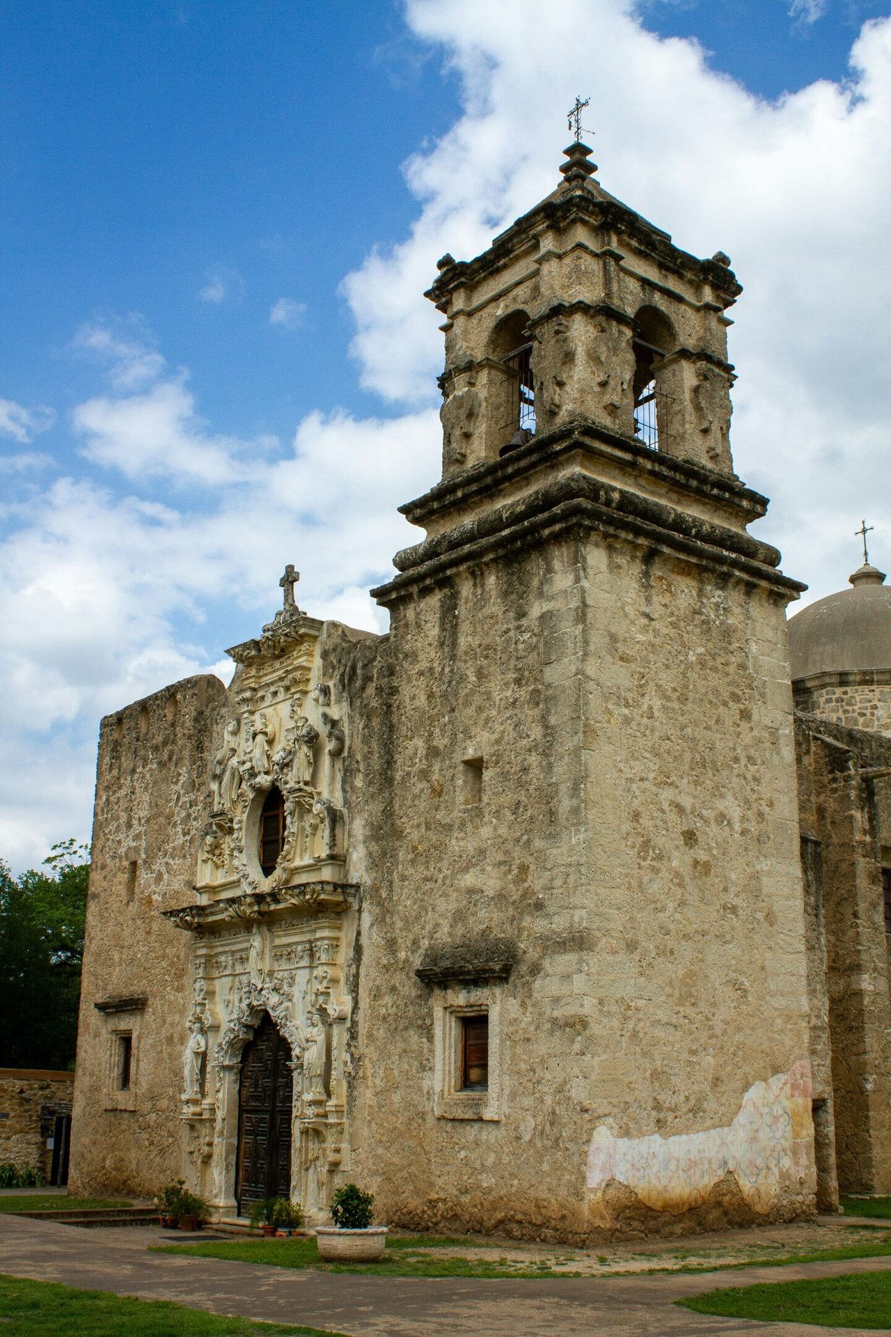 Mission San Jose, a historic stone church in Texas, with an ornate facade and bell tower.
