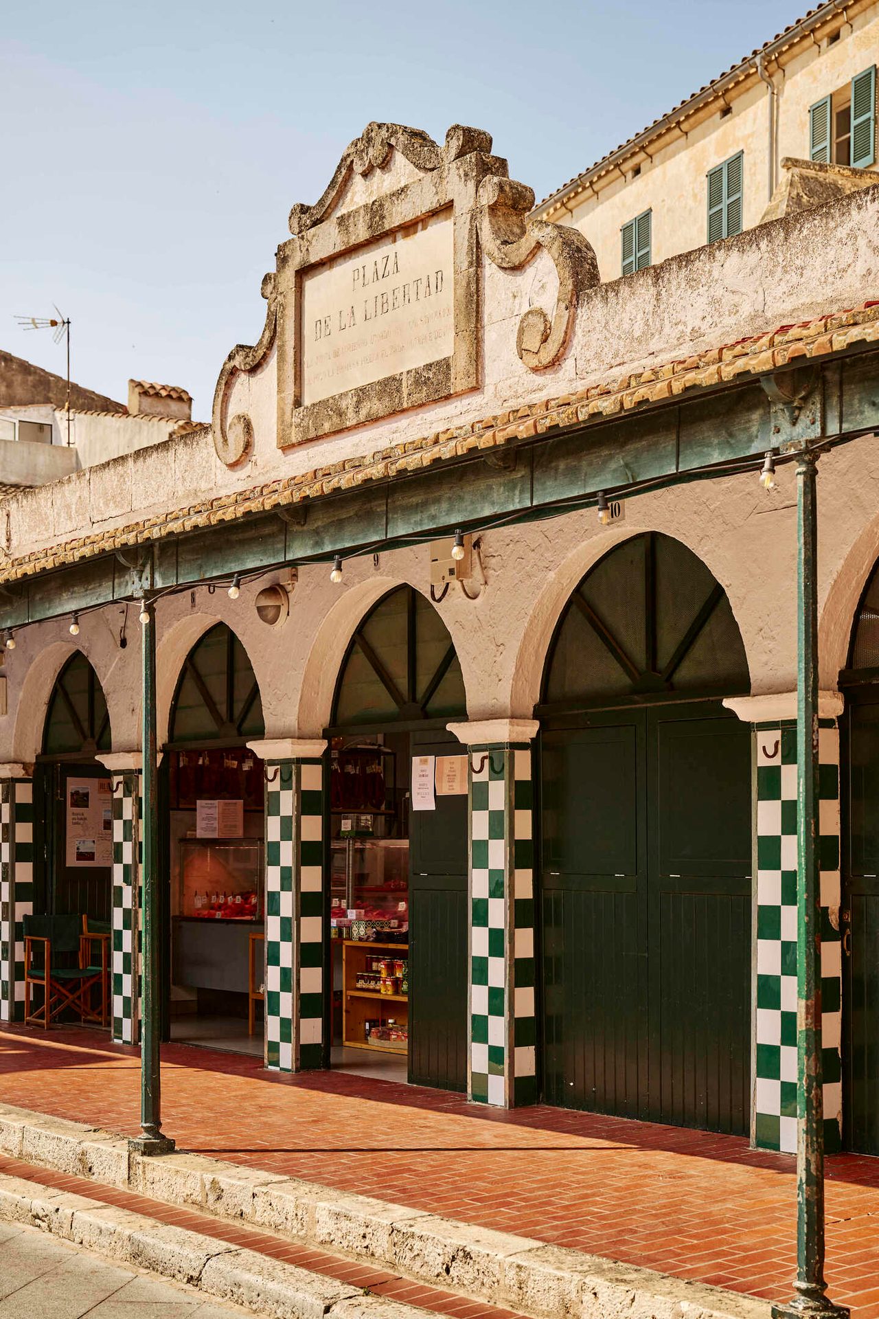 Arched market building with green & white checkered pillars, signed "Plaza de la Libertad".