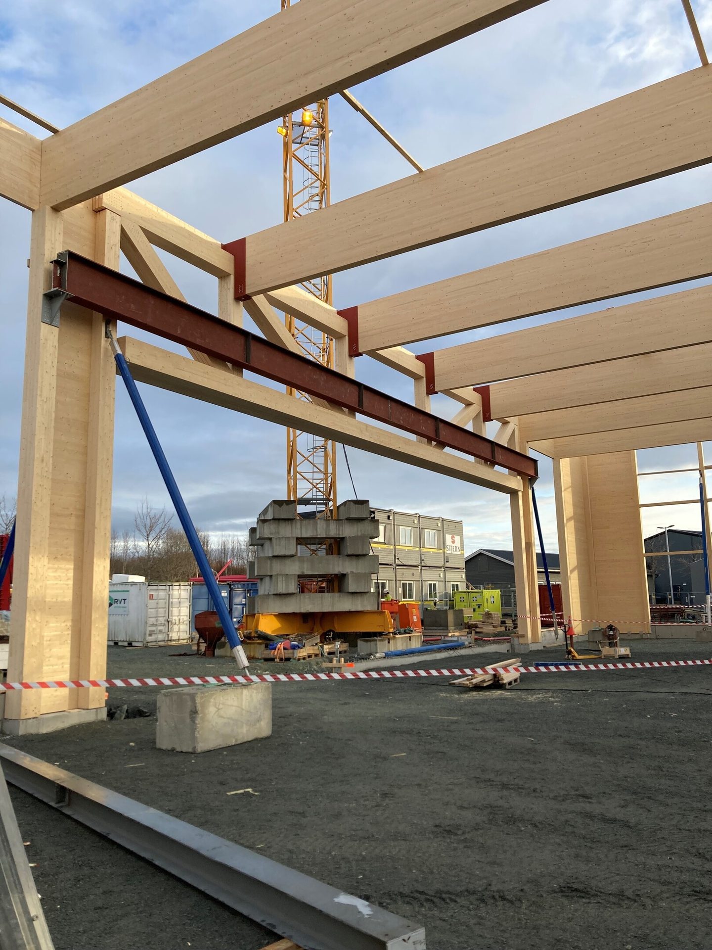 Large timber and steel frame building under construction, with a crane.