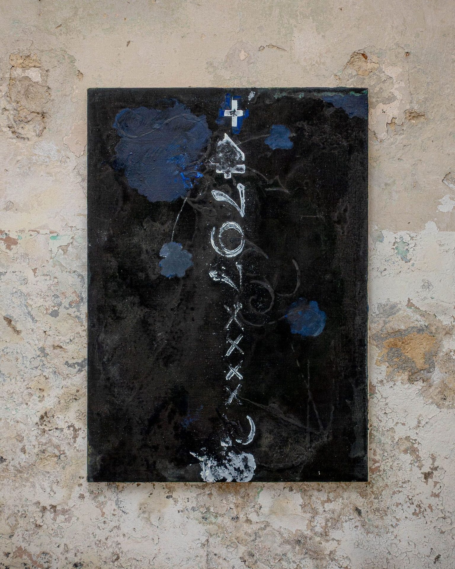 Dark painting with white markings & blue elements on a peeling wall.