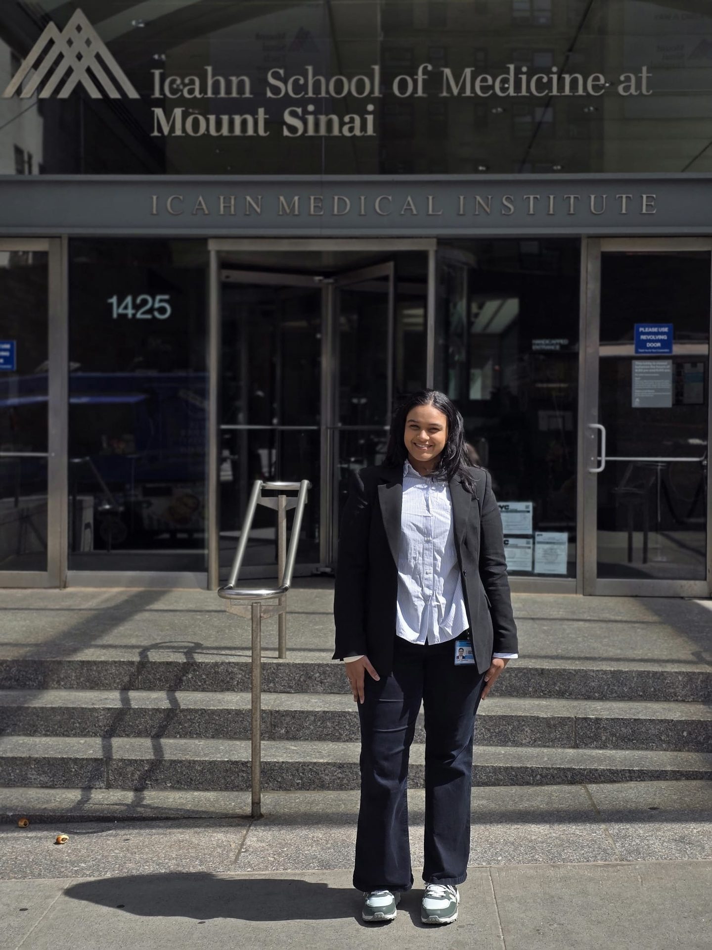 Smiling woman in business casual attire in front of Icahn School of Medicine at Mount Sinai.