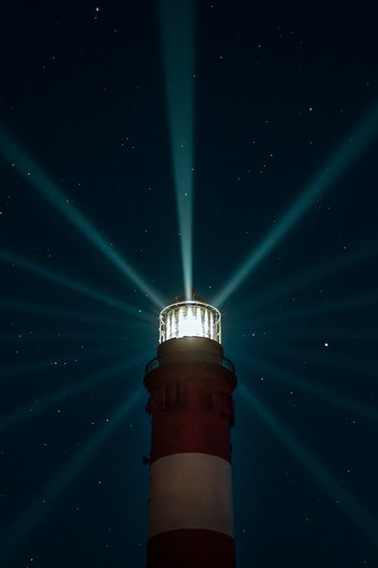 Red and white lighthouse beams cut through a dark, starry night sky.