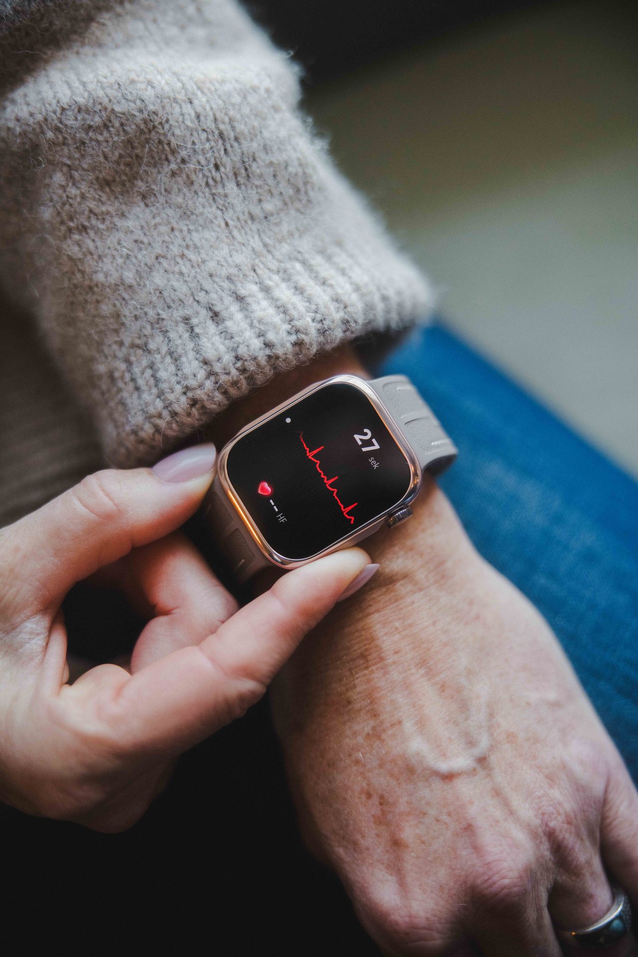 A person's hand wearing a smartwatch displaying a heart rate monitor.