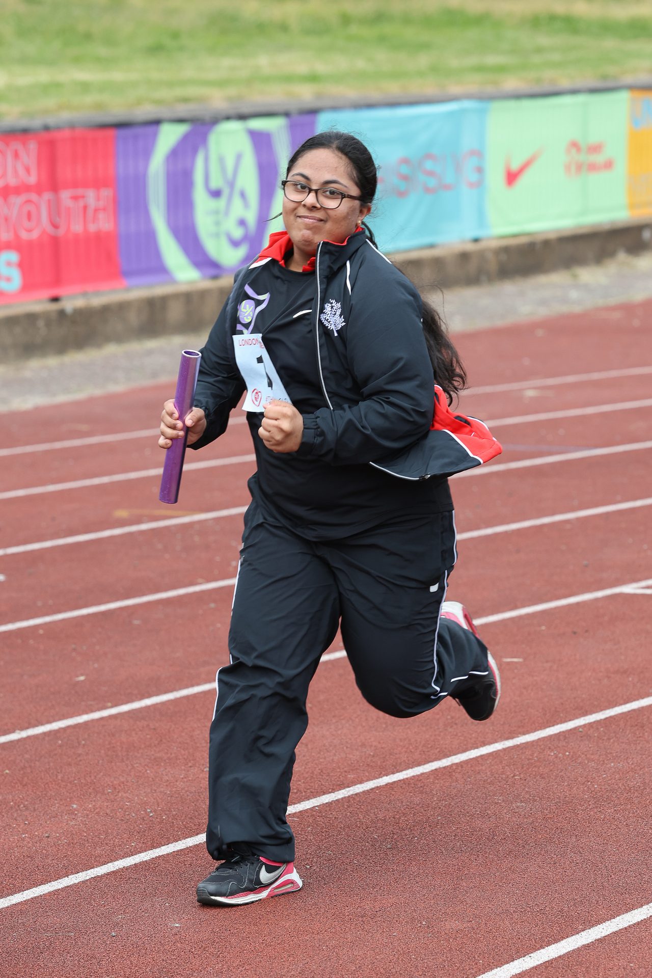 Girl wearing glasses running with a relay baton