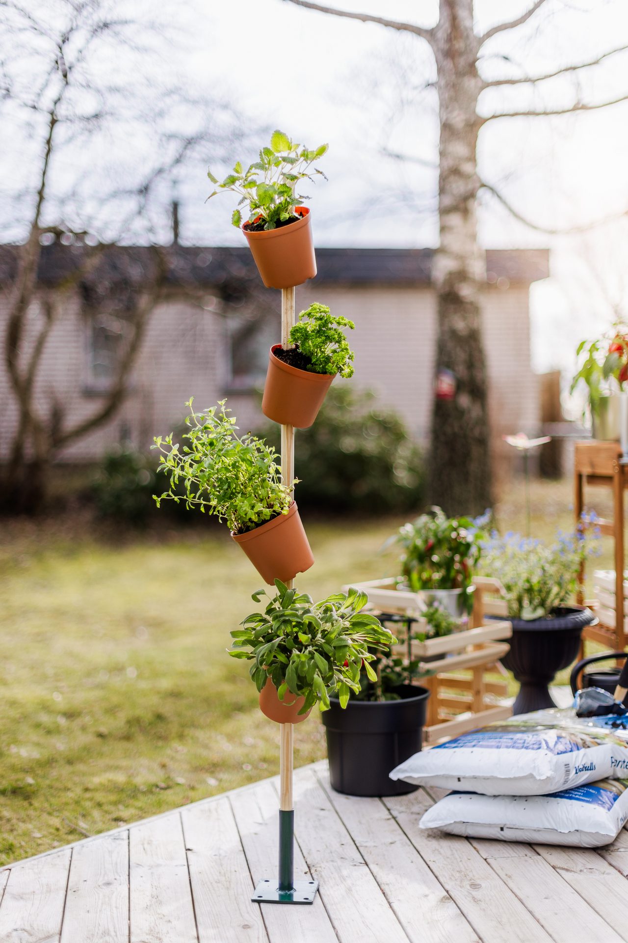 A vertical stack of terracotta pots with green plants on a wooden deck, forming a tiered planter.