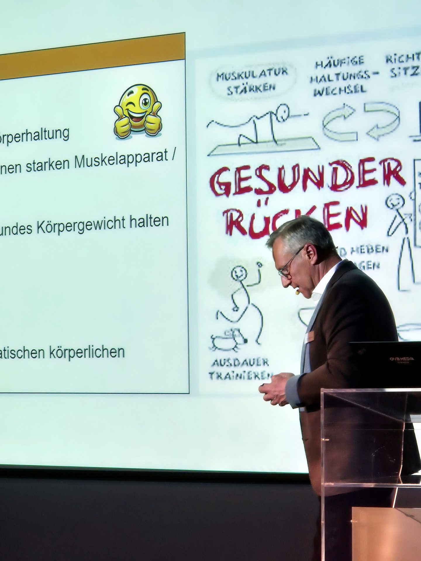 A man presents on stage, with a projector showing slides in German about "GESUNDER RÜCKEN" (Healthy Back) and related health tips, including drawings.