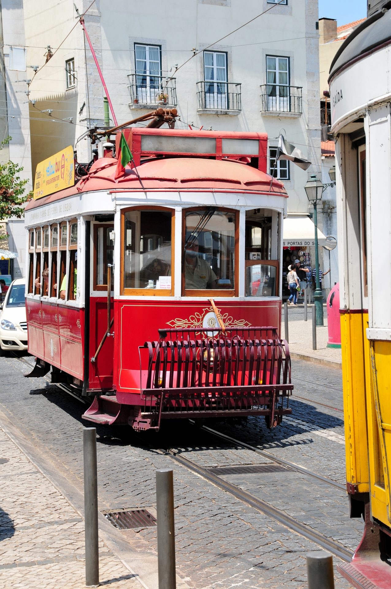 A classic red tram on a cobblestone street in a European city, with traditional buildings.