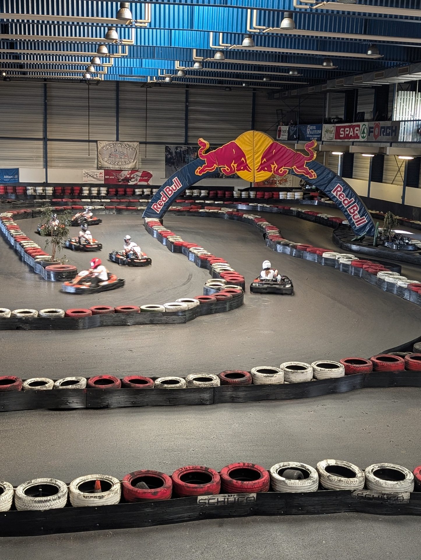 Indoor go-kart track with karts, tire barriers, and a large Red Bull arch.
