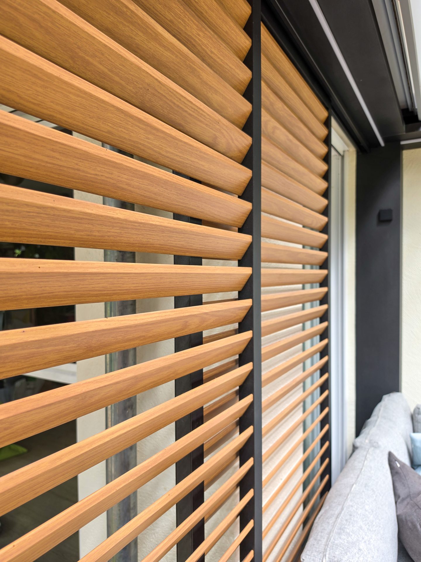Close-up of modern wooden louvered outdoor blinds in a warm brown tone, providing shade and privacy.