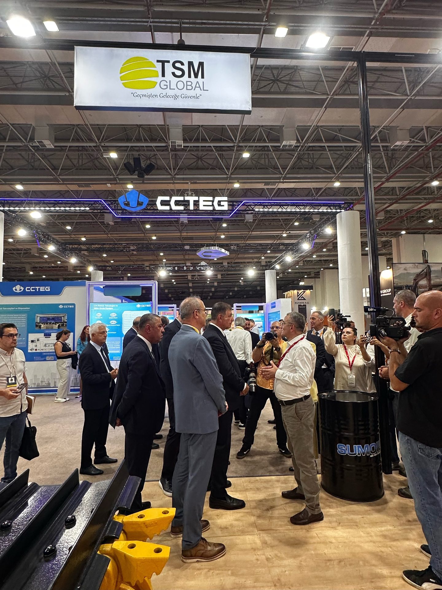 Trade show with TSM GLOBAL, CCTEG signs, people, and industrial displays.