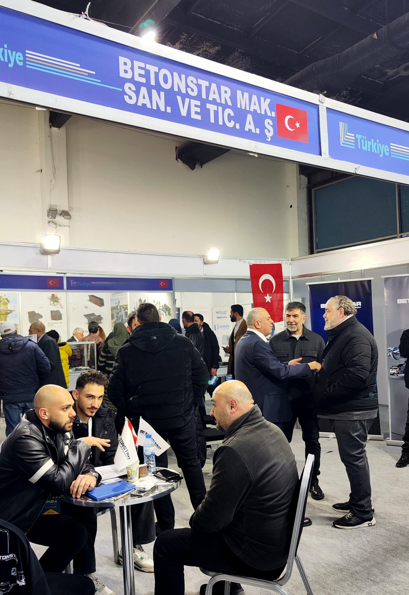 Attendees at a BETONSTAR trade show booth, with Turkish flags visible.