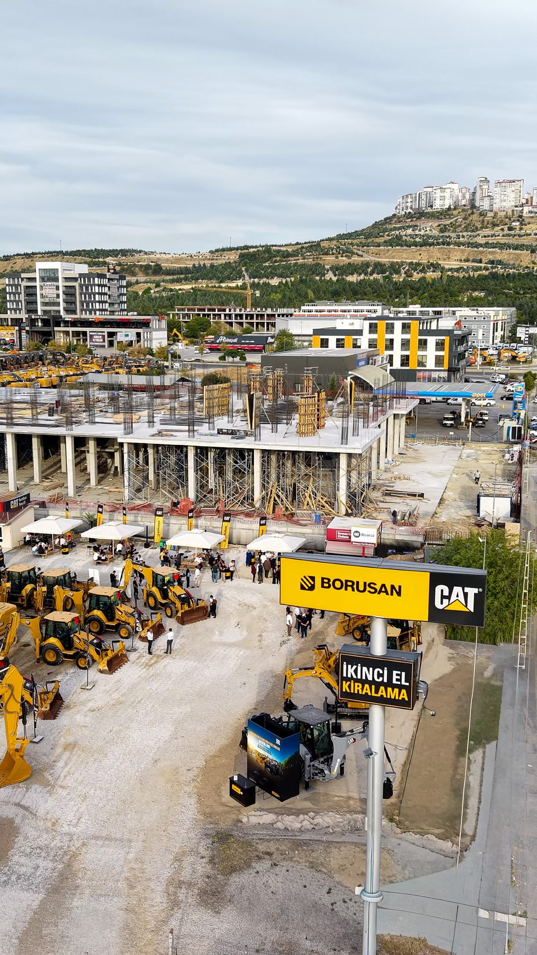 Aerial view: Borusan CAT event with yellow construction vehicles, people, and buildings.