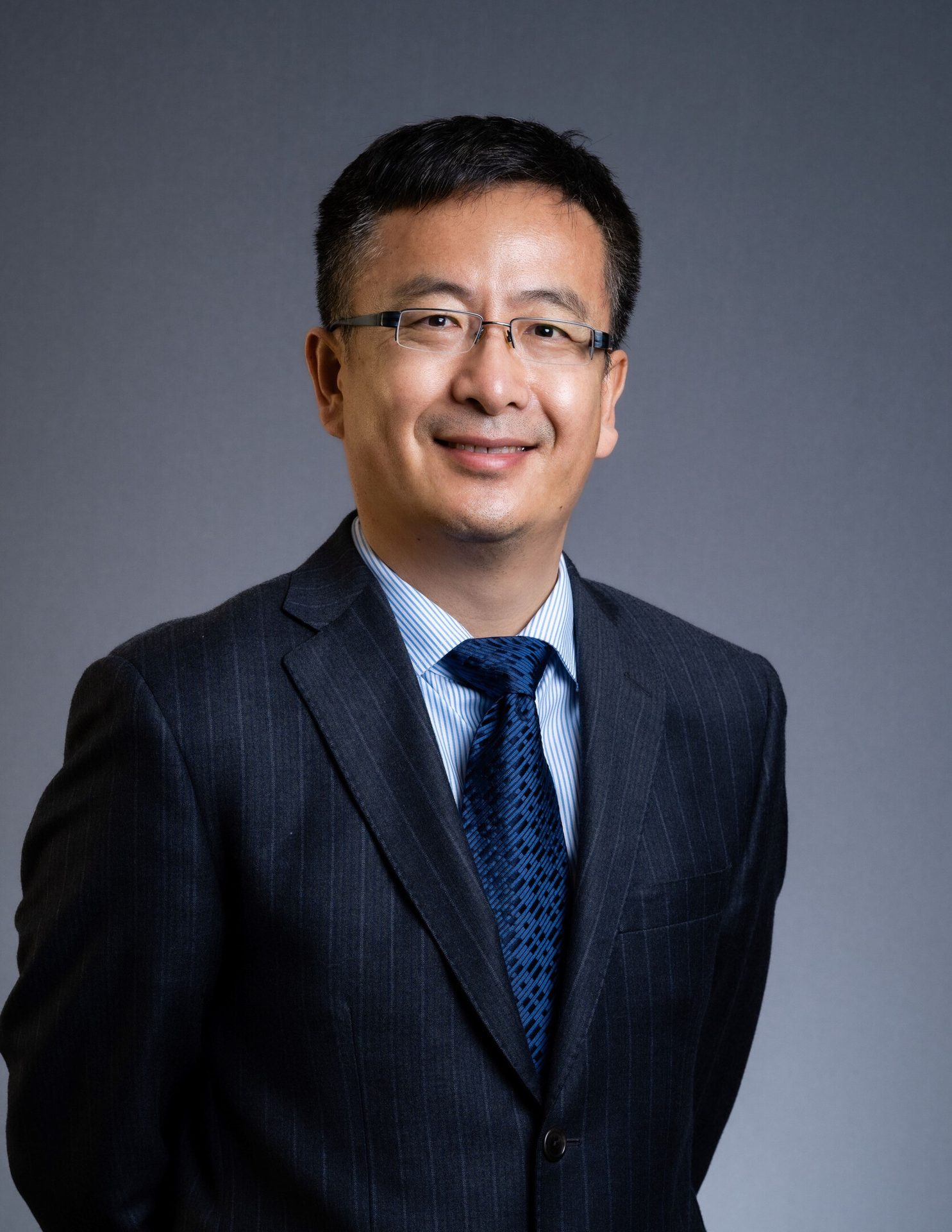 Smiling man in suit and tie with glasses.