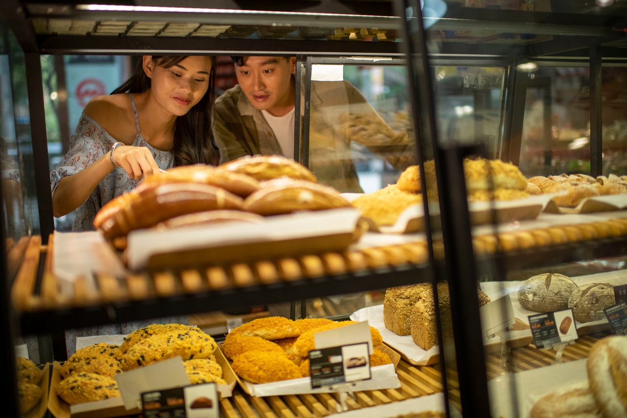 People, Hand, Glass counter, Case, Baked goods, Signs, Shelves