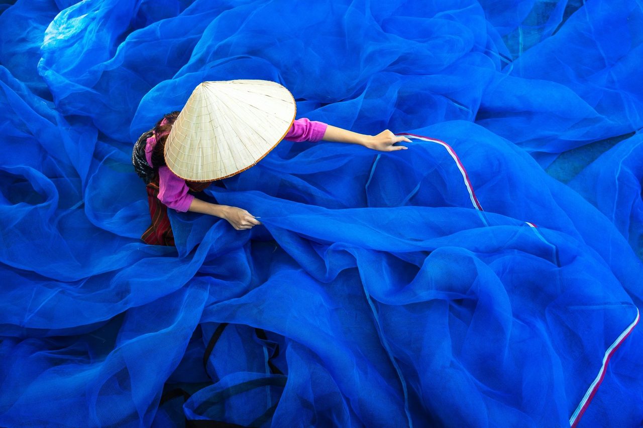 Asian woman organizing blue ocean nets 