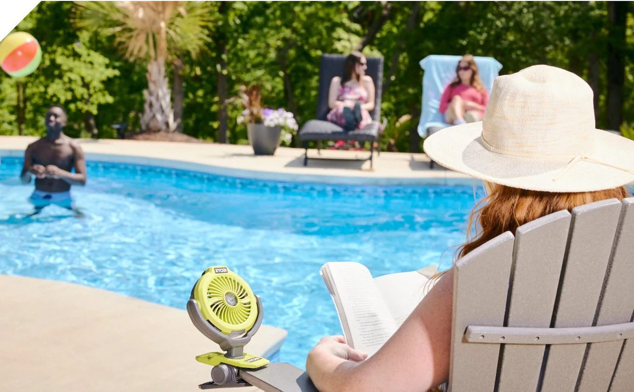 Woman reading by a pool with a Ryobi portable fan.
