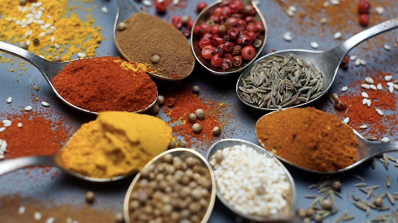 Indian and Asian food spices on spoons and dark background