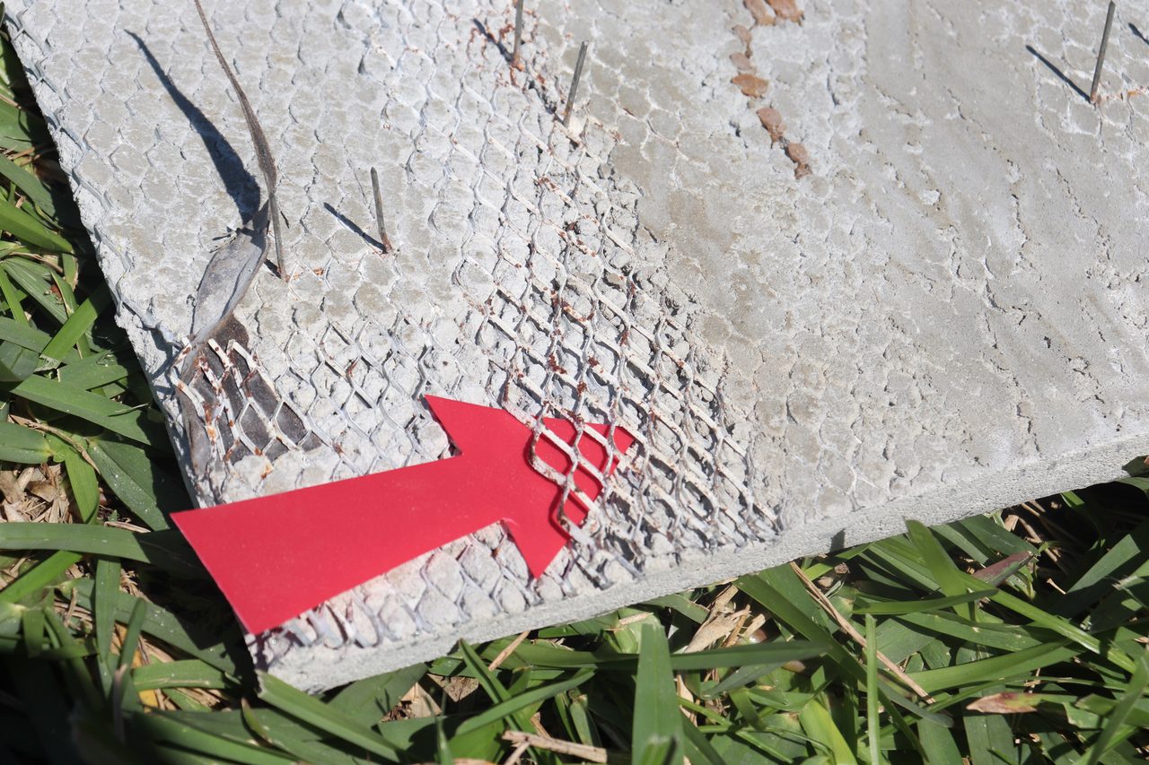 This image shows areas where the lath has been fully embedded on all sides by the stuccoas well as areas red arrow, where the lath is fully free-floating, with no embedment. The areas where embedment is insufficient are prone to issues from moisture penetration and corrosion.