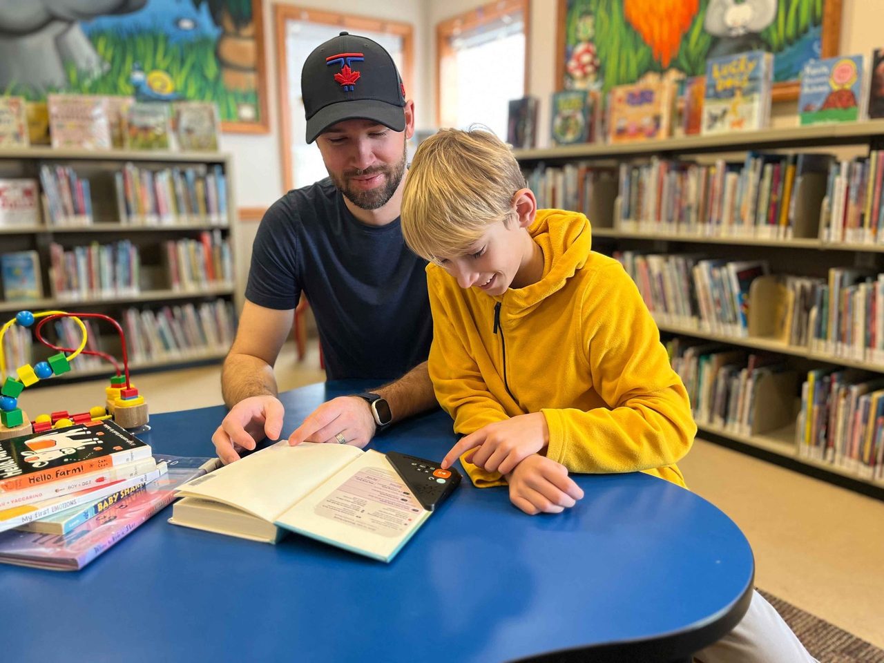 A young boy reads a book with his dad using the wonderbook device