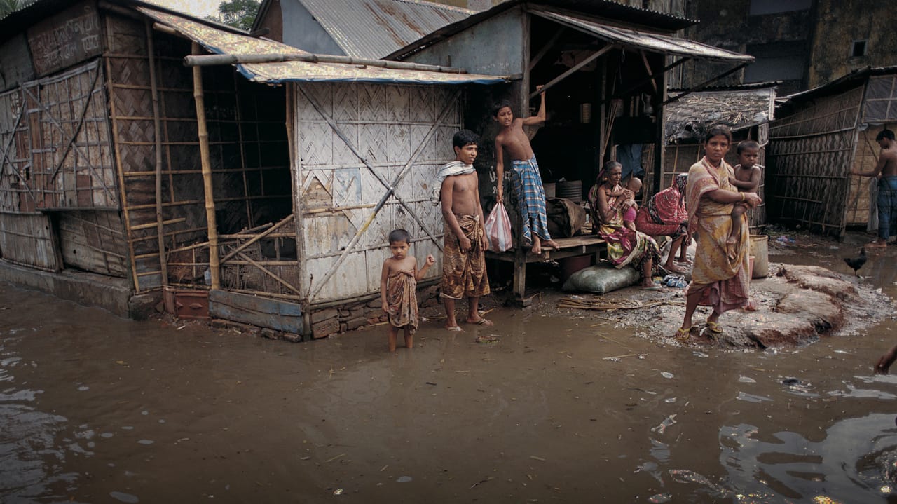 Photo a family in the tropics, wading through ankle high water surrounding their poor and rickety house.