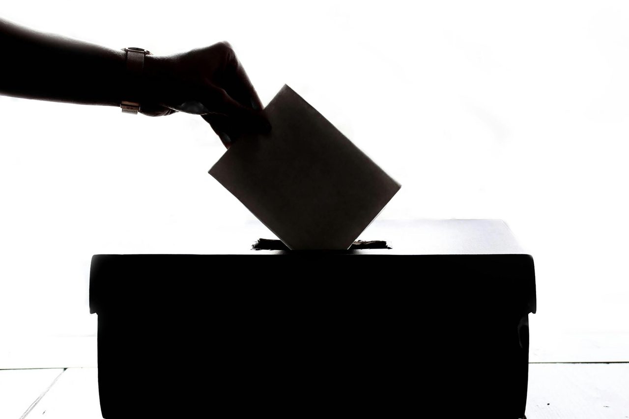 Silhouette of a hand placing a vote into a ballot box, symbolizing democracy.. Element5 Digital: https://www.pexels.com/@element5