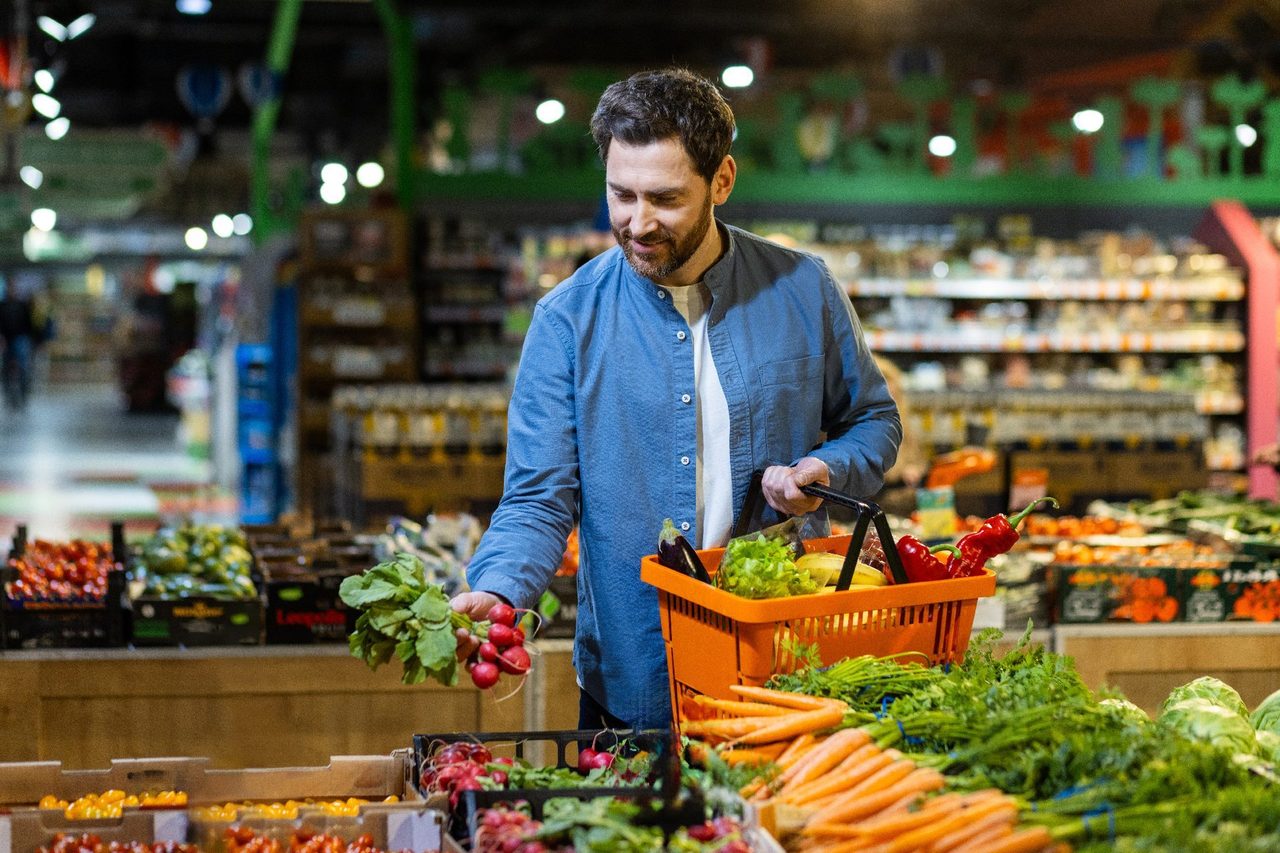 Smiling man selecting fresh produce in a grocery store.