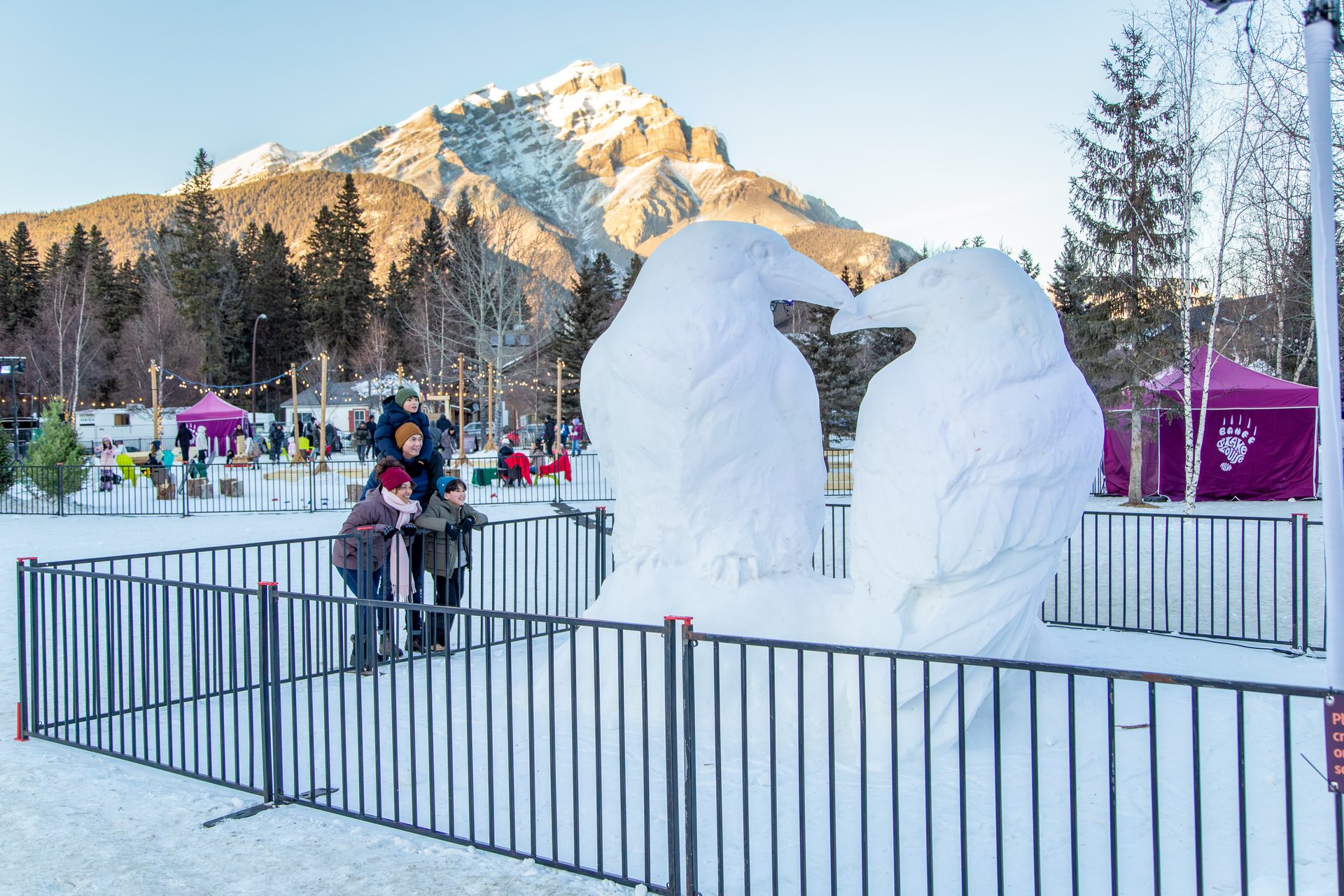 Family and snow bird sculptures at a winter mountain festival.