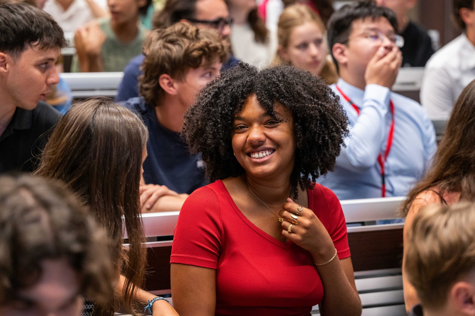 Smiling young Black woman with curly hair in a lecture hall.