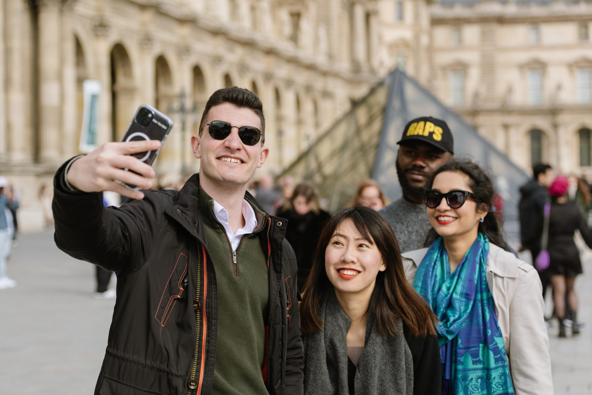Diverse group takes a selfie at the Louvre Museum.