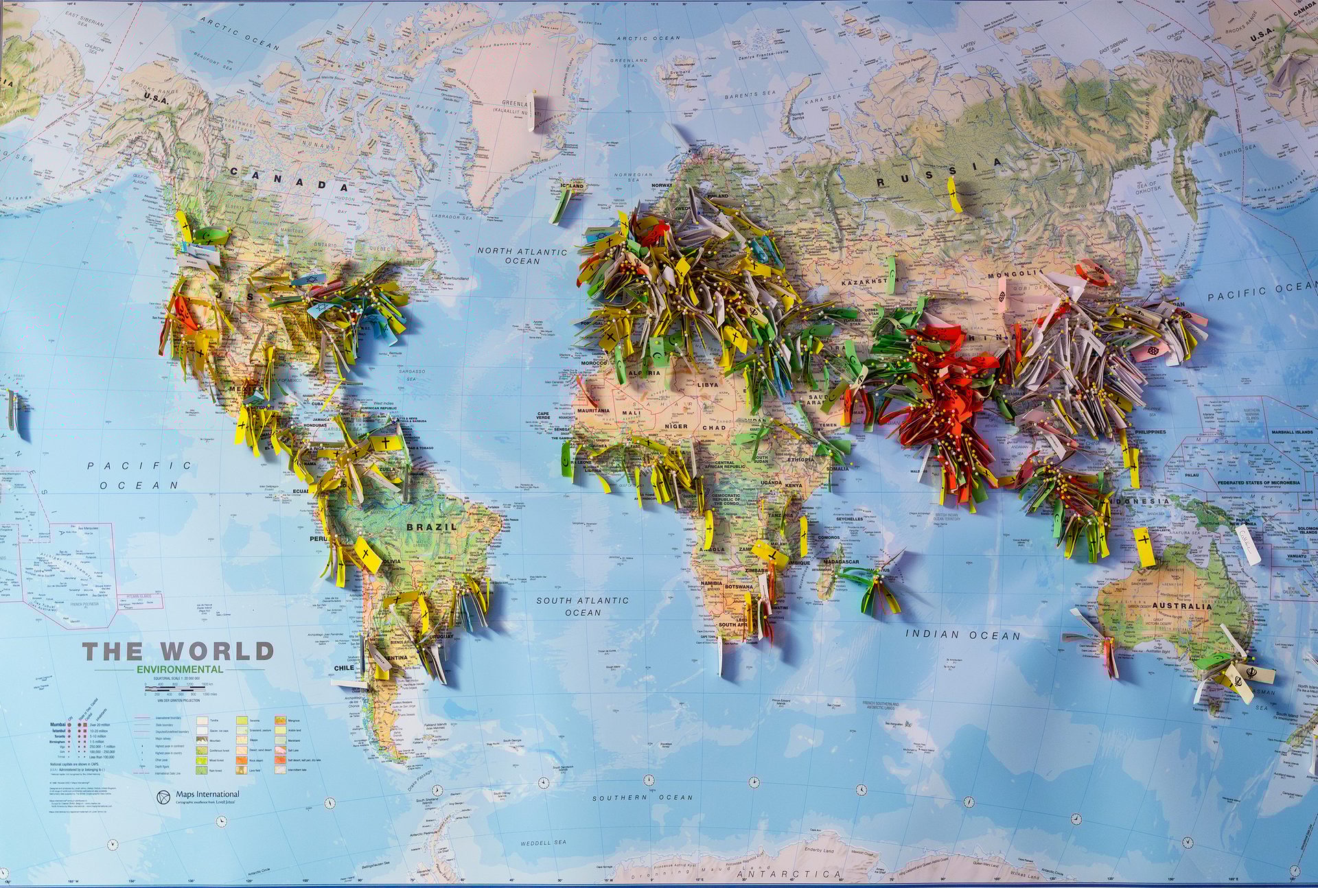A world map covered in colorful paper flags and pins.
