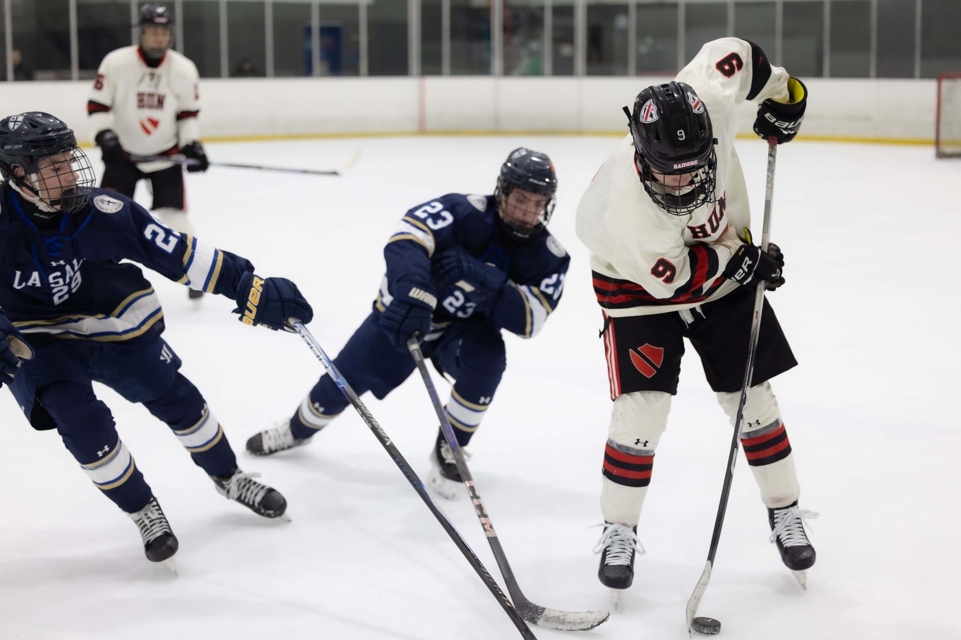 Three hockey players battle for the puck on an ice rink during a game.